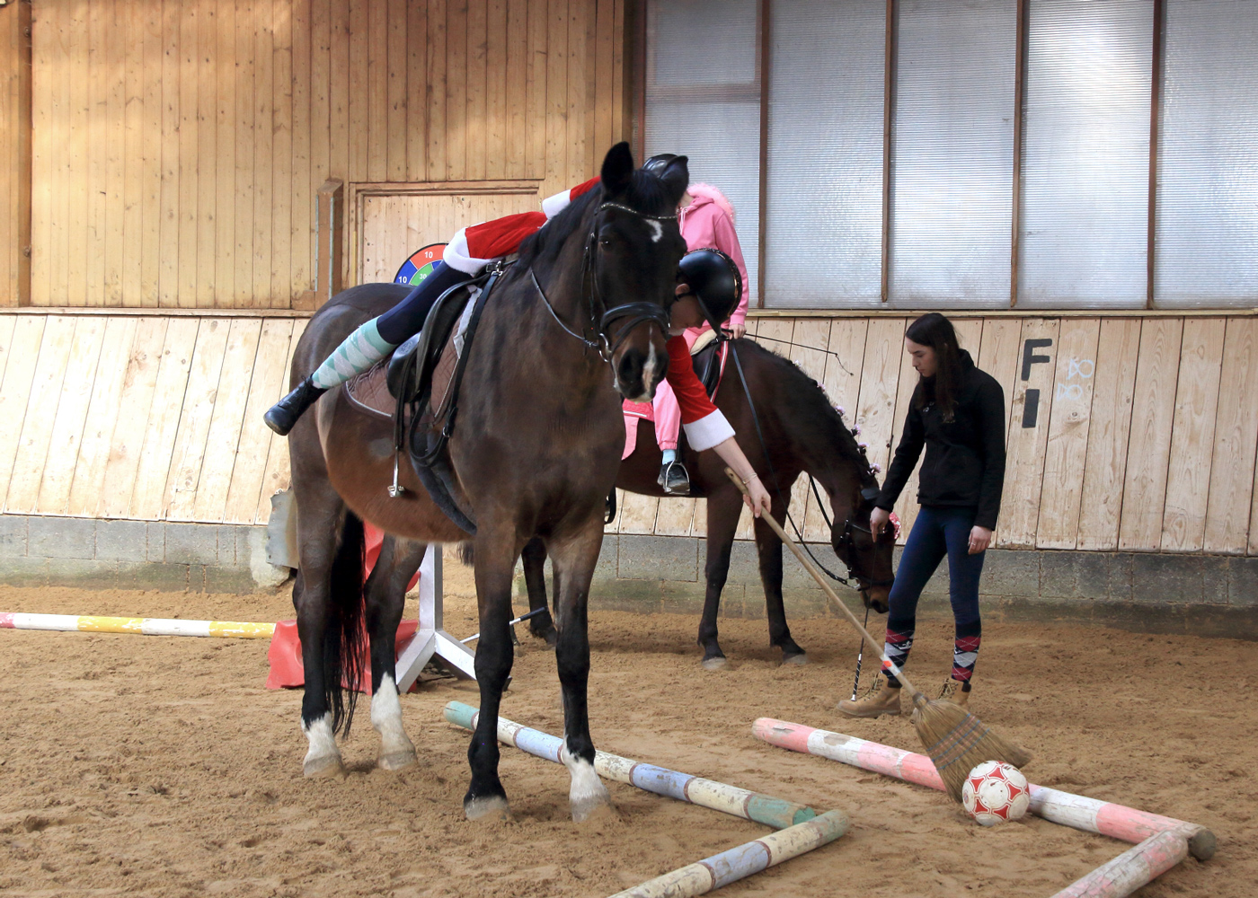 Ein Kind, das auf dem Pferd sitzt schiebt einen Ball mit einem Besen